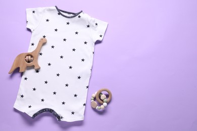 Photo of Baby onesie and accessories on violet background, flat lay. Space for text