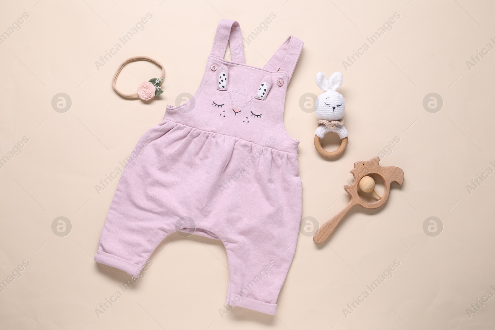 Baby jumpsuit and accessories on beige background, flat lay Photo of Baby jumpsuit and accessories on beige background, flat lay