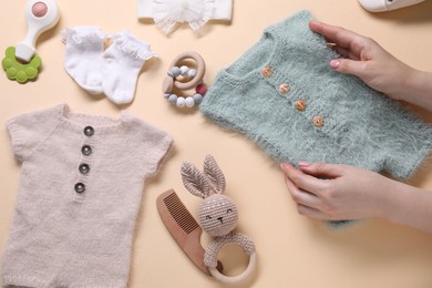 Photo of Woman with baby clothes and accessories on beige background, top view