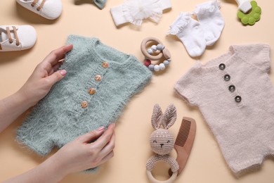 Photo of Woman with baby clothes and accessories on beige background, top view