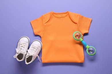 Photo of Bright baby onesie, accessory and shoes on violet background, flat lay