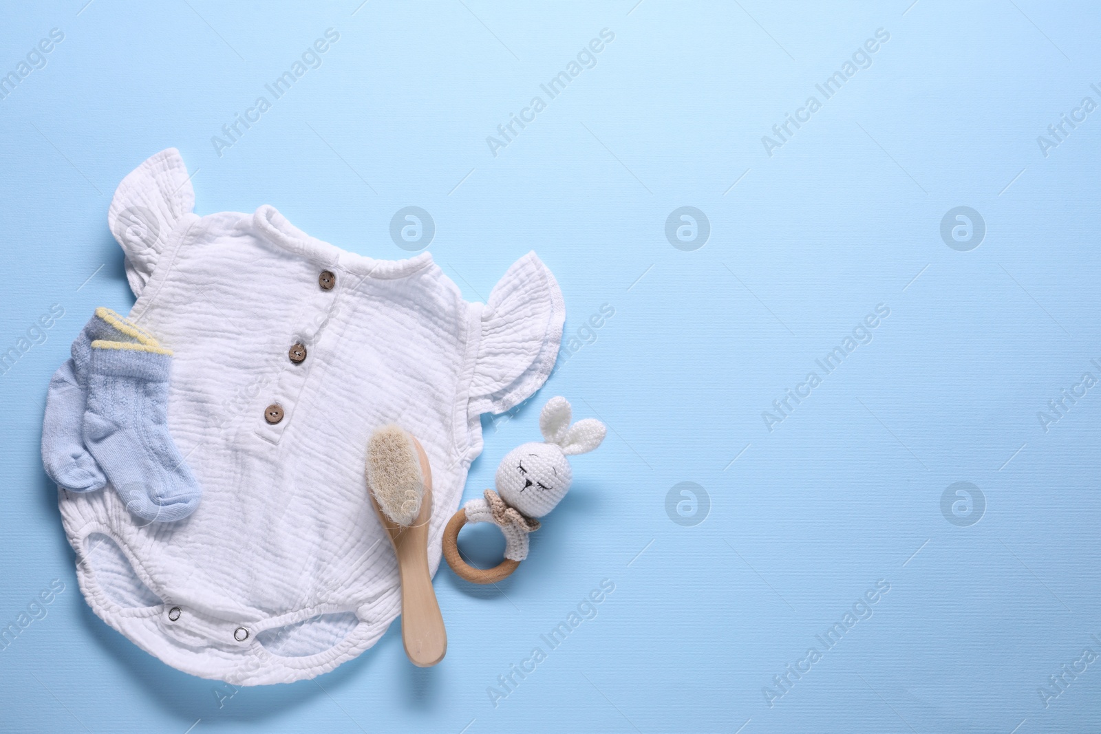 Photo of Baby clothes and accessories on light blue background, flat lay. Space for text