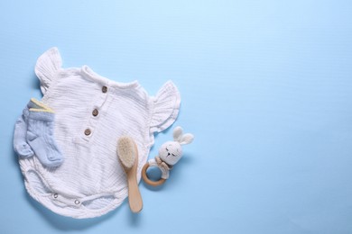 Photo of Baby clothes and accessories on light blue background, flat lay. Space for text