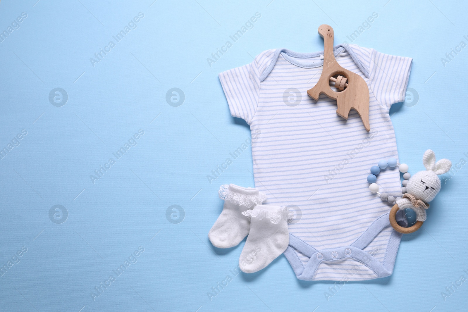 Photo of Baby clothes and accessories on light blue background, flat lay. Space for text