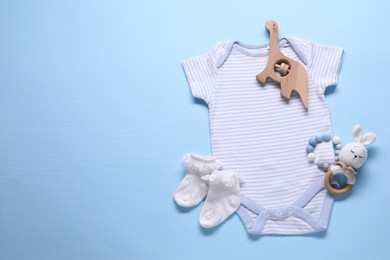 Photo of Baby clothes and accessories on light blue background, flat lay. Space for text