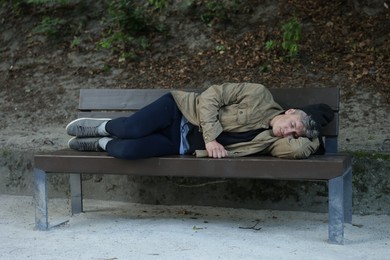 Photo of Homeless man sleeping on bench in park