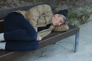 Photo of Homeless man sleeping on bench in park