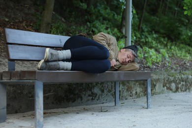 Photo of Homeless man sleeping on bench in park