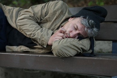 Photo of Homeless man sleeping on bench in park