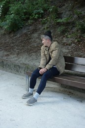 Photo of Homeless man sitting on bench in park