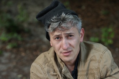 Photo of Portrait of poor homeless man outdoors, space for text