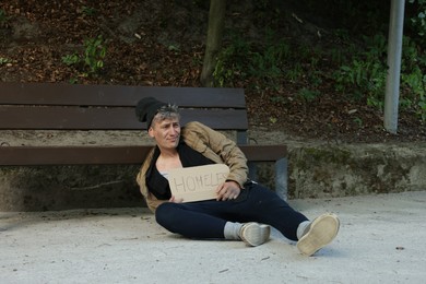 Photo of Poor man with sign Homeless near bench in park