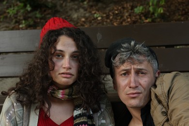 Photo of Poor homeless people near bench in park