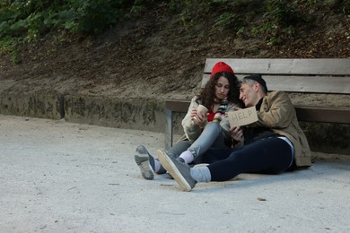 Photo of Homeless people with sign Help near bench in park, space for text