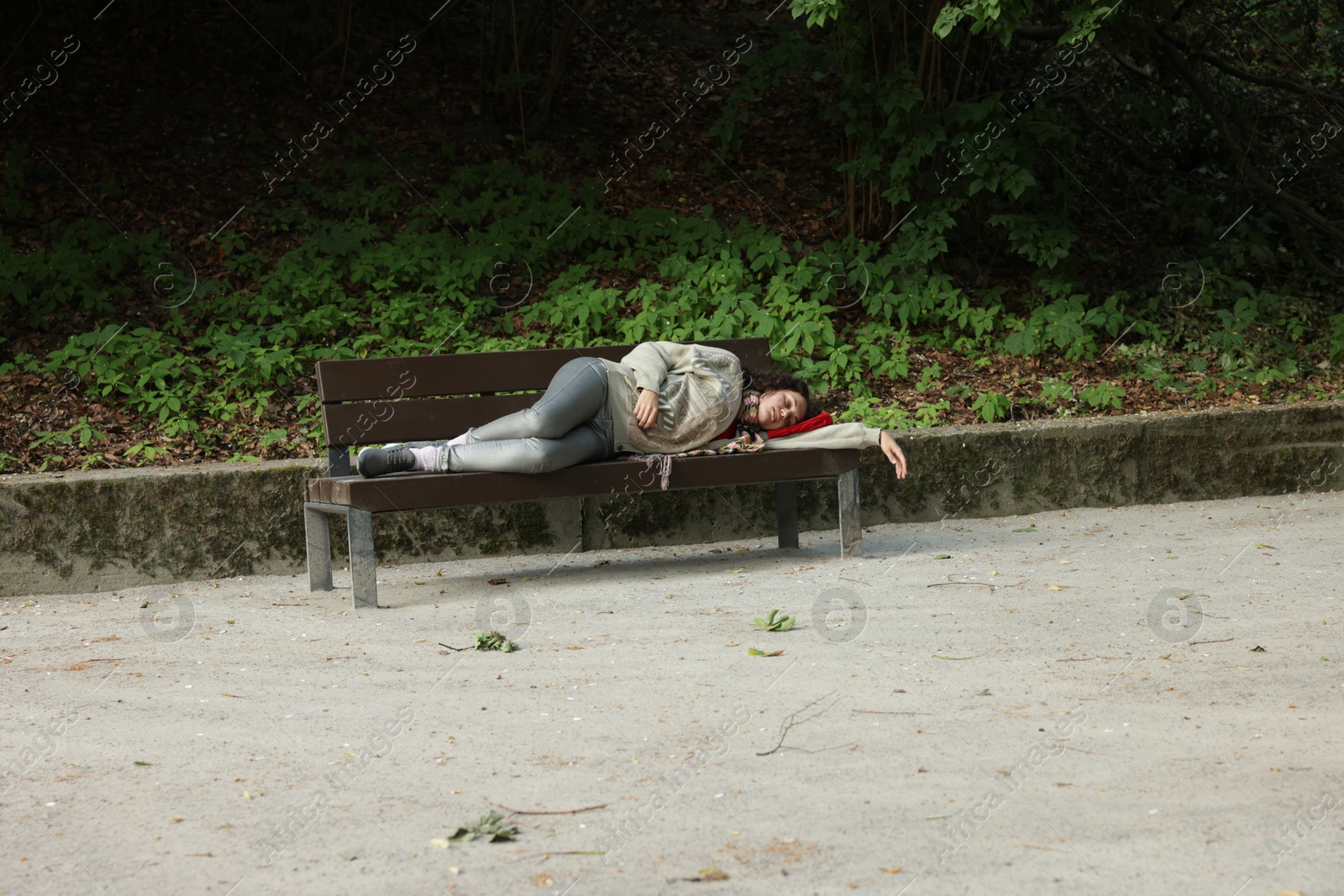 Photo of Homeless woman sleeping on bench in park