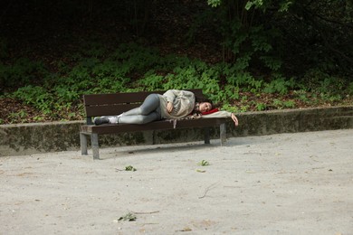 Photo of Homeless woman sleeping on bench in park
