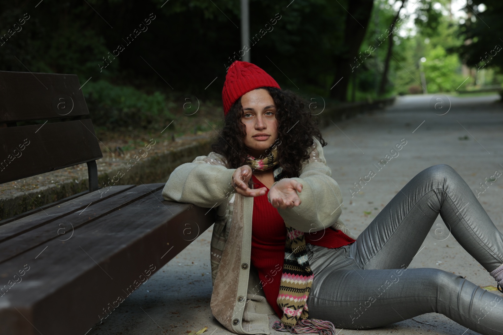 Photo of Homeless woman begging for money near bench in park