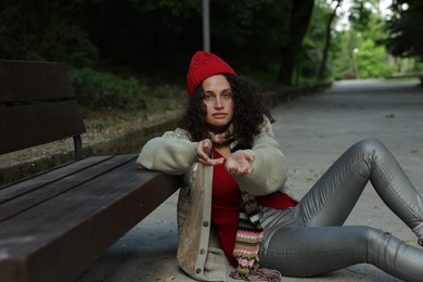 Photo of Homeless woman begging for money near bench in park