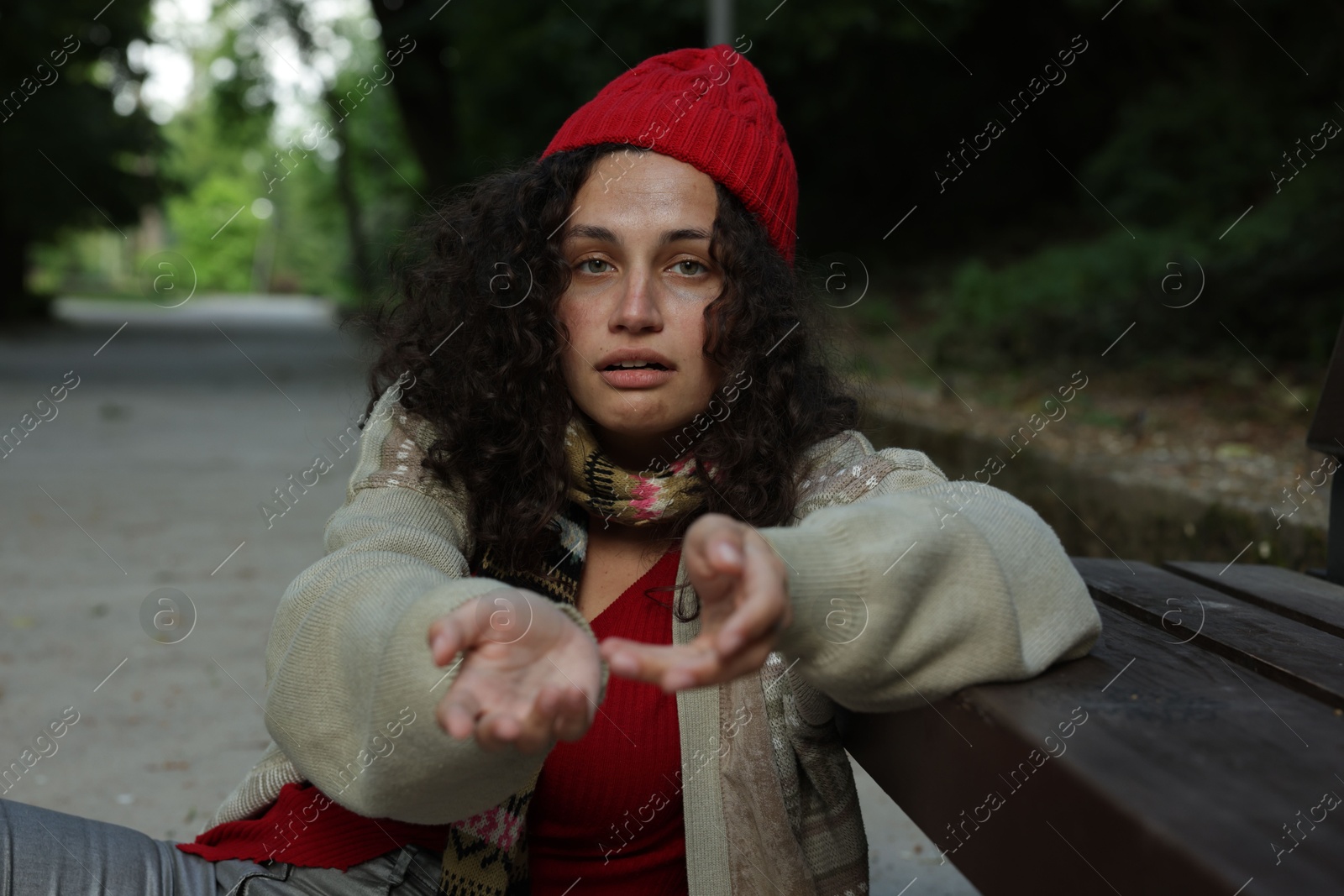 Photo of Homeless woman begging for money near bench in park
