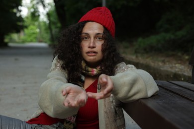 Photo of Homeless woman begging for money near bench in park