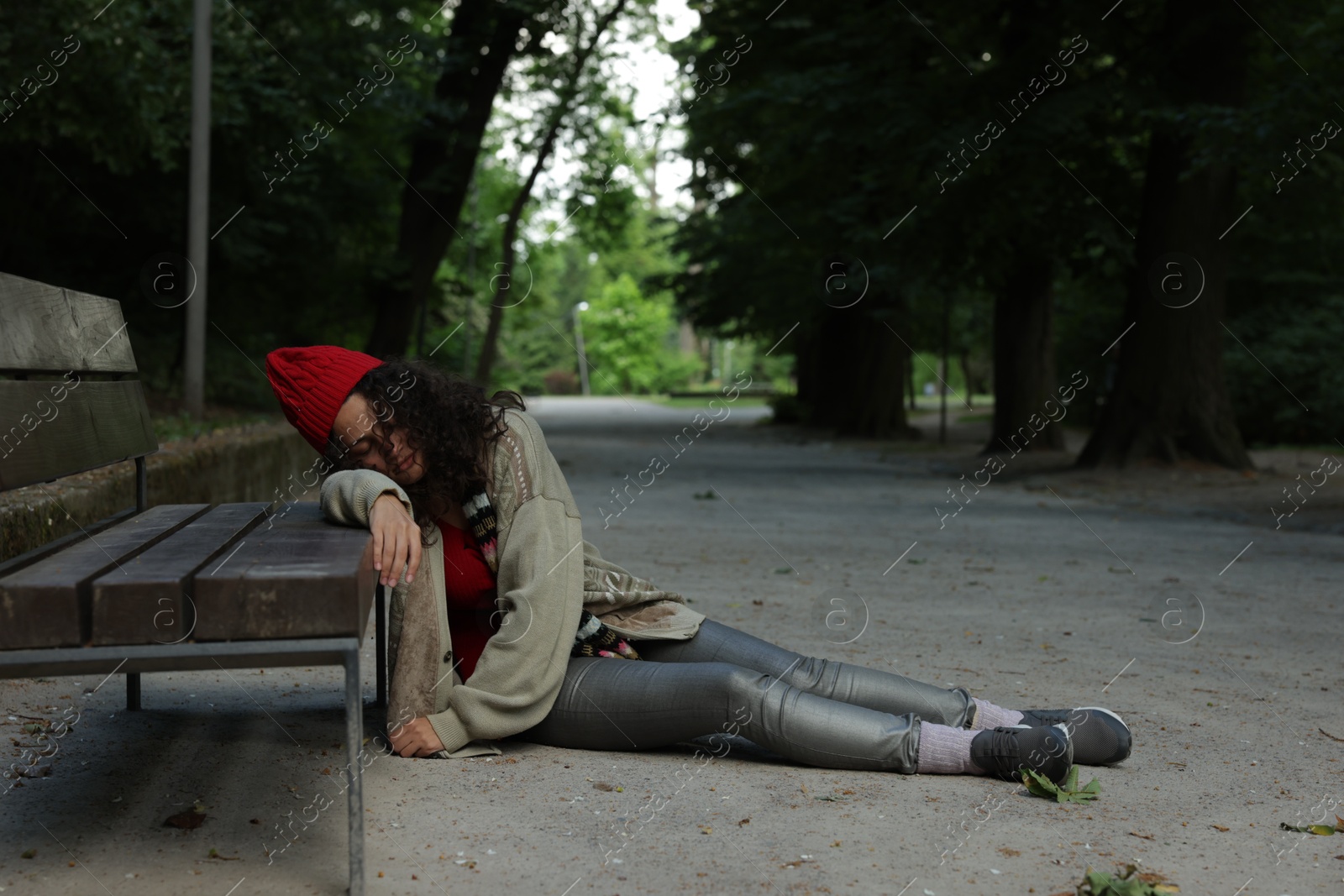 Homeless woman sleeping near bench in park Photo of Homeless woman sleeping near bench in park