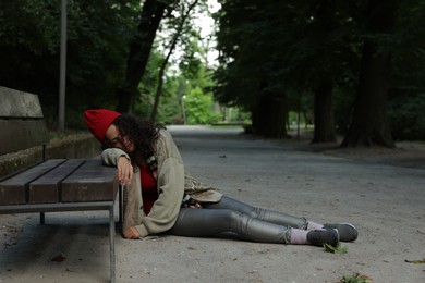 Photo of Homeless woman sleeping near bench in park