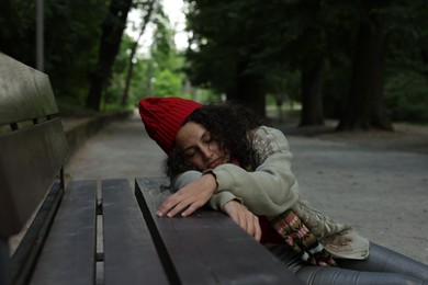 Photo of Homeless woman sleeping near bench in park