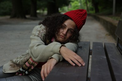 Photo of Poor homeless woman near bench in park