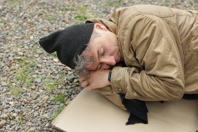 Photo of Homeless man sleeping on carton in park