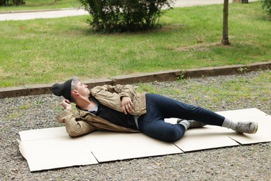 Photo of Homeless man lying on carton in park