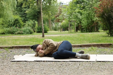 Photo of Homeless man sleeping on carton in park