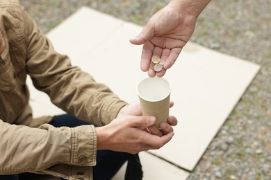 Photo of Man giving money to homeless person outdoors, closeup