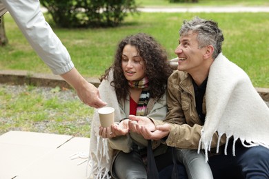 Photo of Man giving money to homeless people in park, closeup