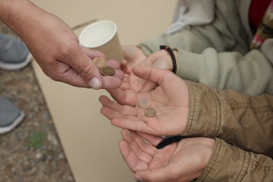 Photo of Man giving money to homeless people outdoors, closeup