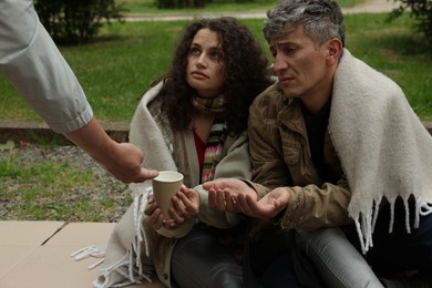 Photo of Man giving money to homeless people in park, closeup