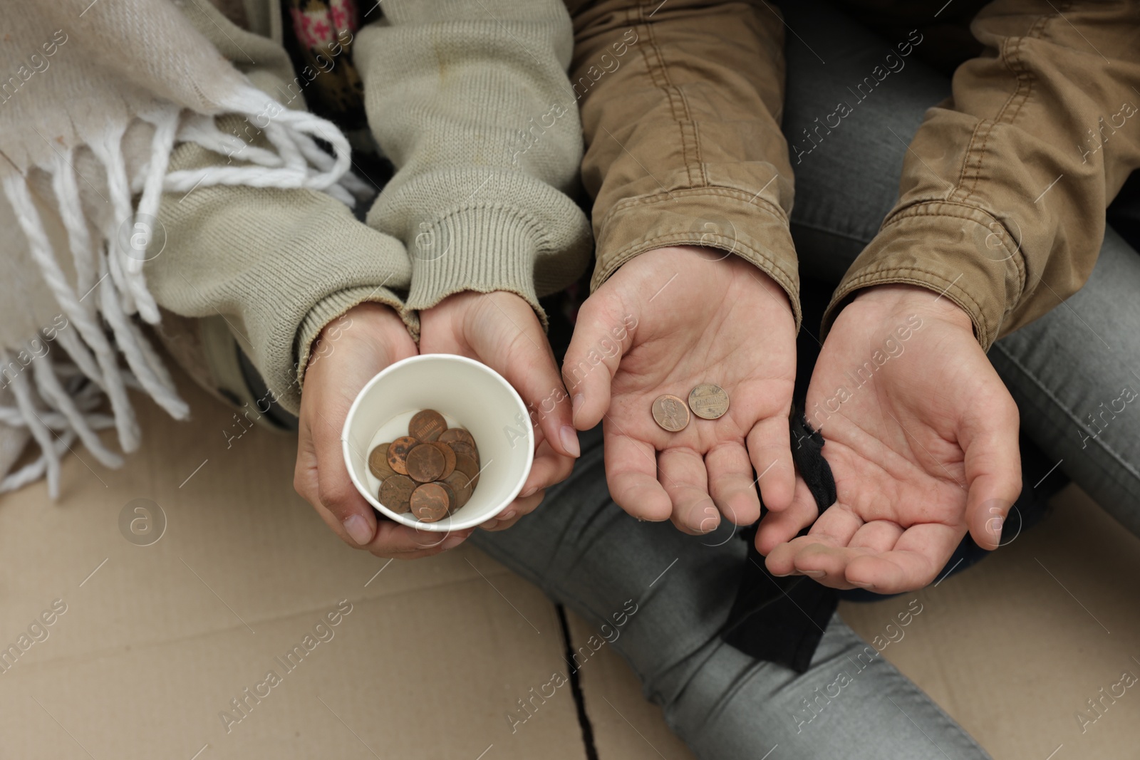 Photo of Homeless people with paper cup and coins begging for money on carton outdoors, above view