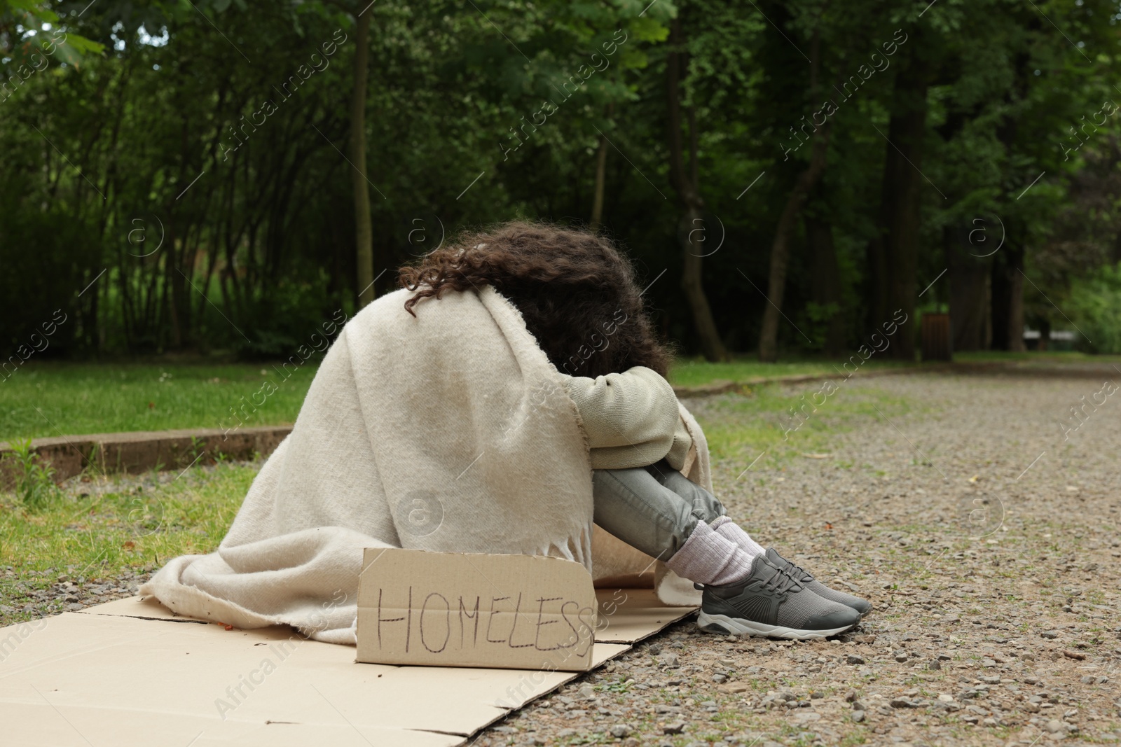 Photo of Poor woman with sign Homeless on carton in park