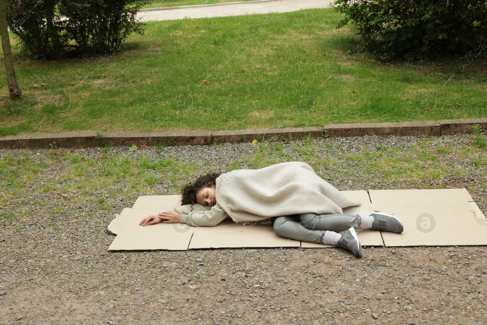 Photo of Homeless woman sleeping on carton in park