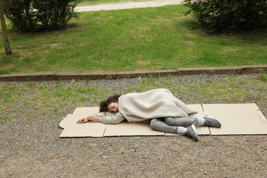 Photo of Homeless woman sleeping on carton in park
