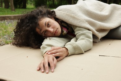 Photo of Homeless woman lying on carton in park
