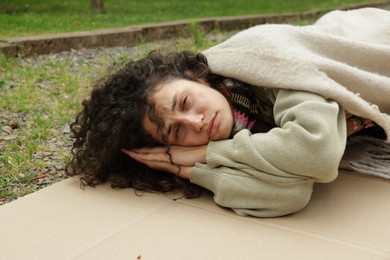 Photo of Homeless woman lying on carton in park