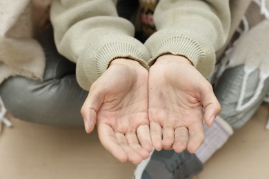 Photo of Homeless woman begging for money outdoors, closeup