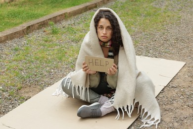 Photo of Homeless woman with sign Help on carton in park