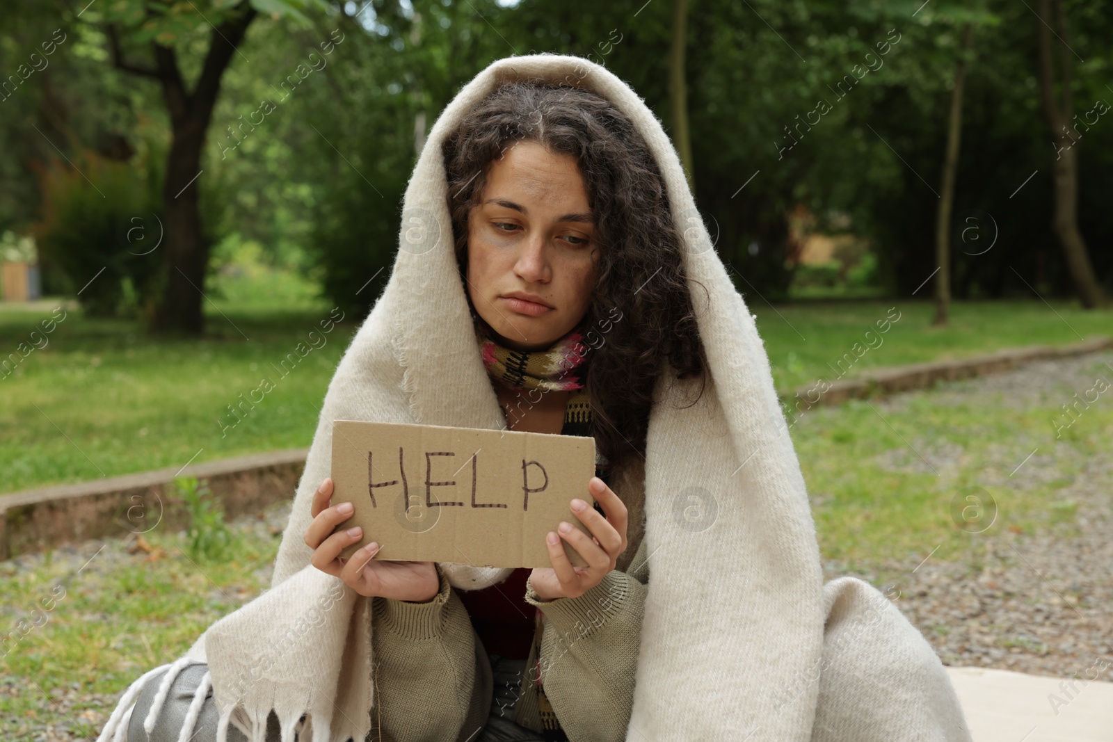 Photo of Homeless woman with sign Help in park