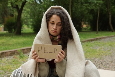 Photo of Homeless woman with sign Help in park