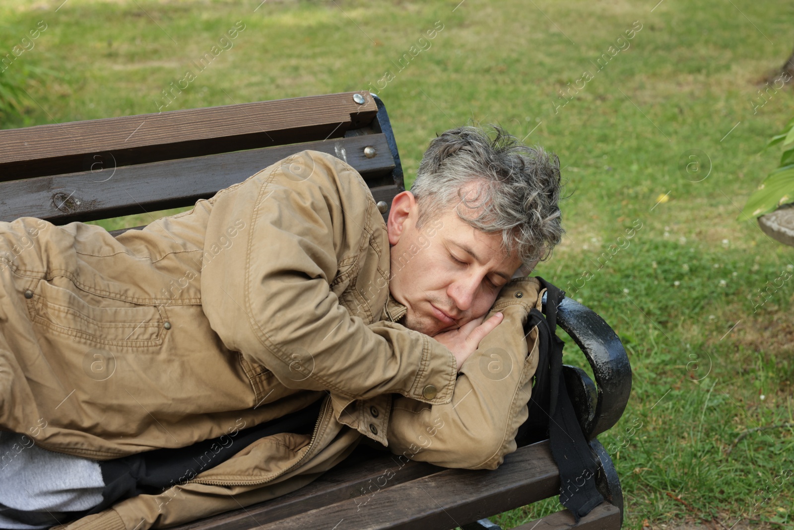 Photo of Homeless man sleeping on bench in park