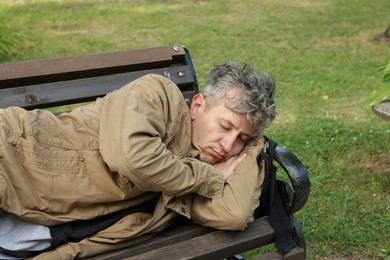 Photo of Homeless man sleeping on bench in park