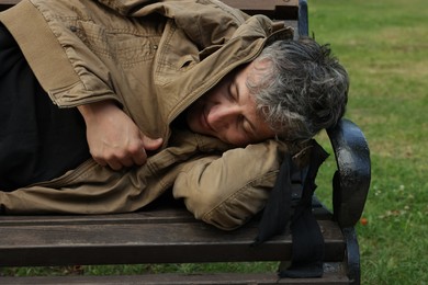 Photo of Homeless man sleeping on bench in park