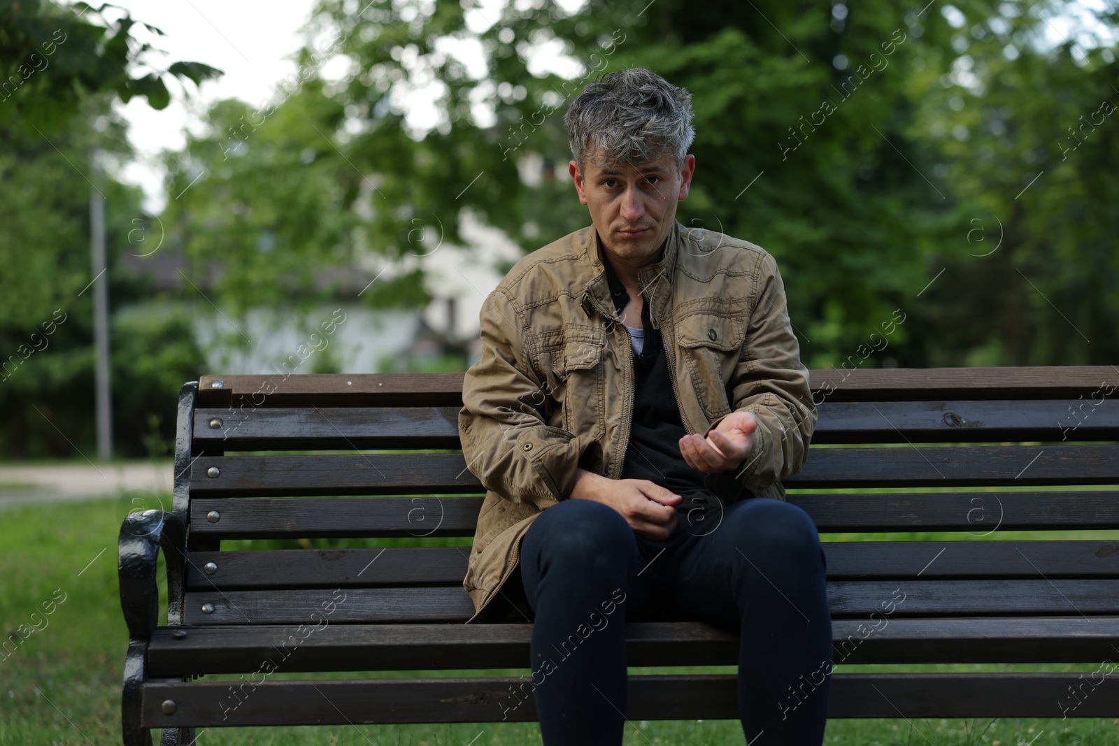 Photo of Homeless man begging for money on bench in park
