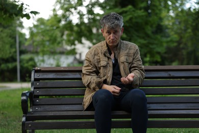 Photo of Homeless man begging for money on bench in park